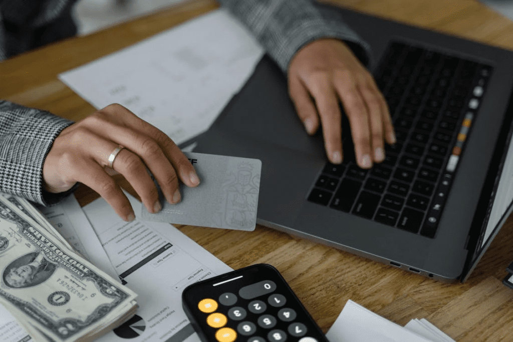 hand holding a card and using a laptop
