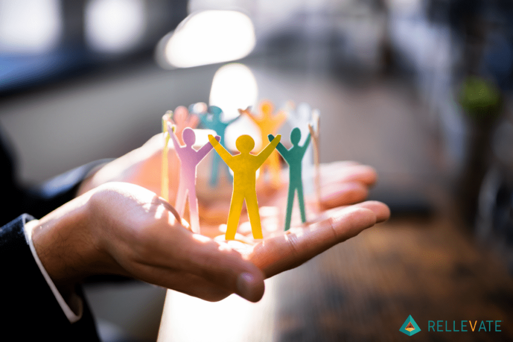 Man holding different colored people made out of paper in both hands