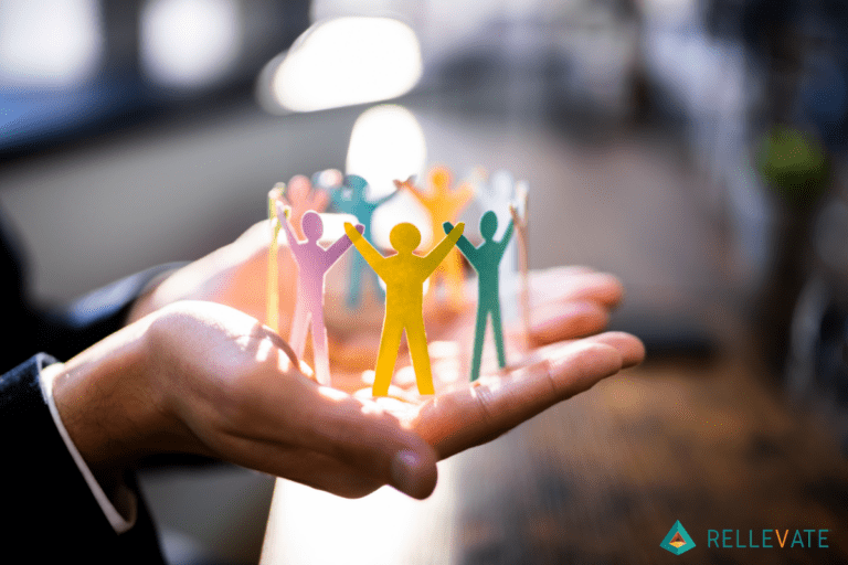 Man holding different colored people made out of paper in both hands