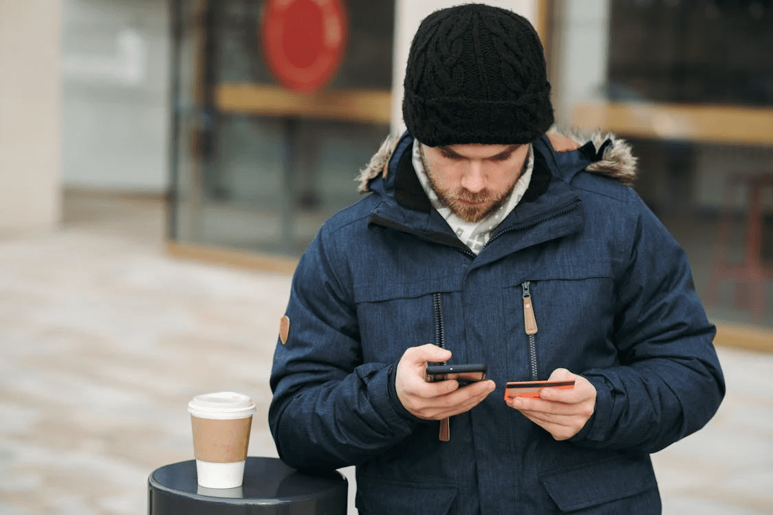 male holding credit card while making payment with smartphone